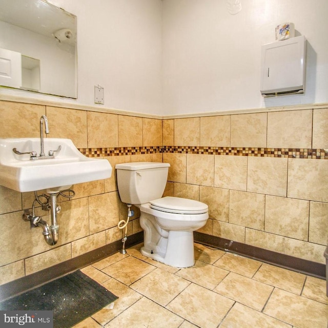 bathroom featuring toilet, sink, and tile walls