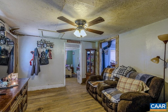 living room featuring ceiling fan, wood-type flooring, and a textured ceiling