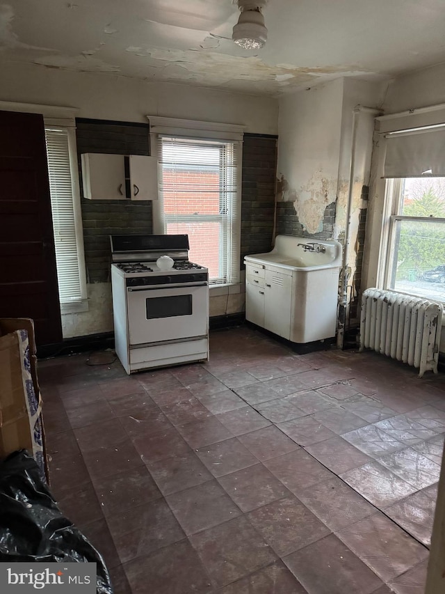 kitchen featuring white cabinetry, white gas range, and radiator heating unit