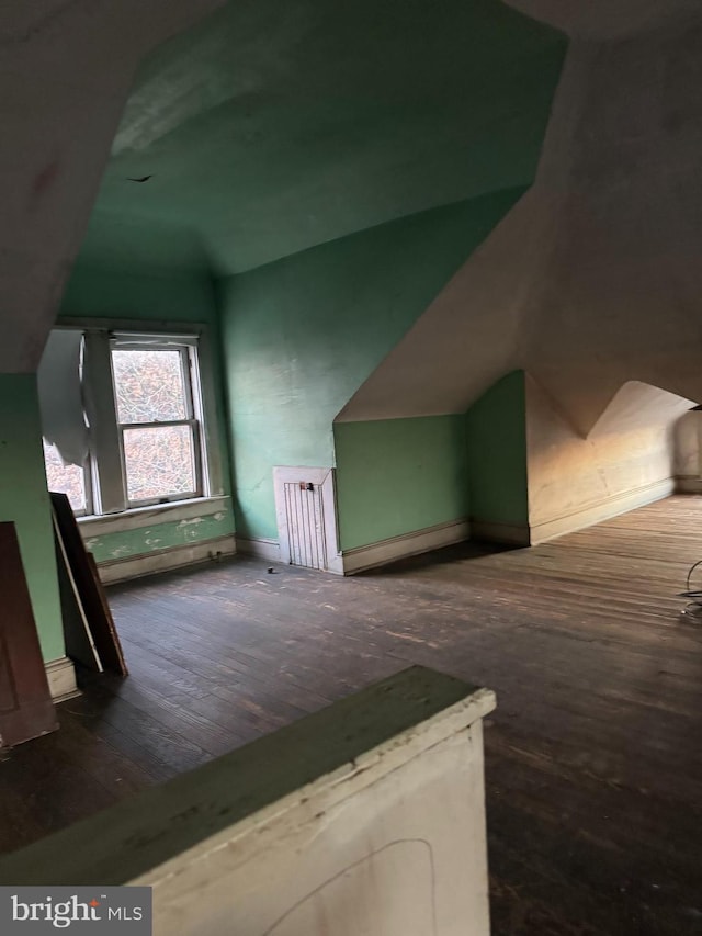 bonus room with dark wood-type flooring and vaulted ceiling