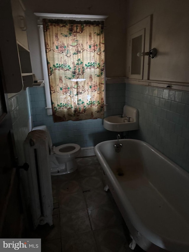 bathroom with a bathtub, radiator, tile patterned floors, toilet, and tile walls