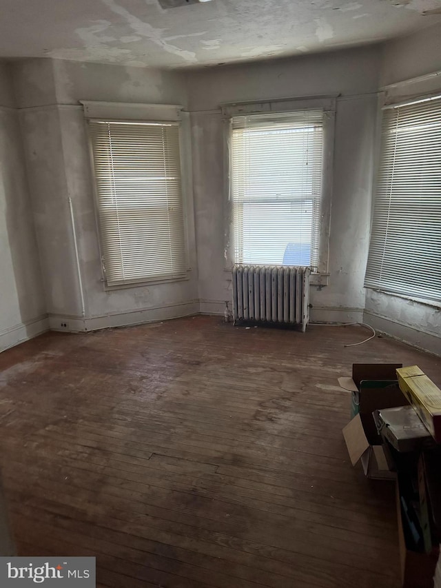 unfurnished room featuring radiator and dark hardwood / wood-style floors