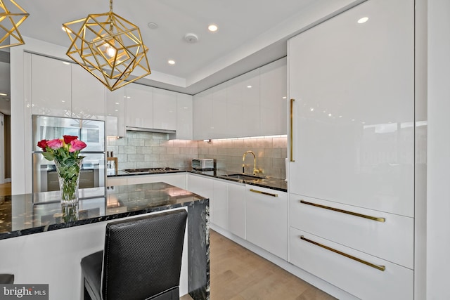 kitchen with pendant lighting, sink, dark stone countertops, appliances with stainless steel finishes, and white cabinetry