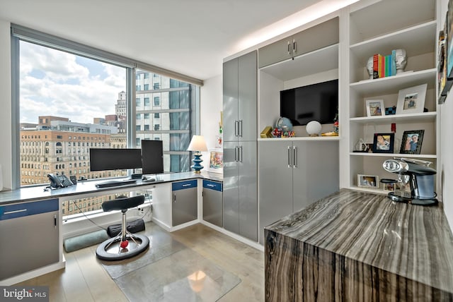 office with light wood-type flooring and built in desk