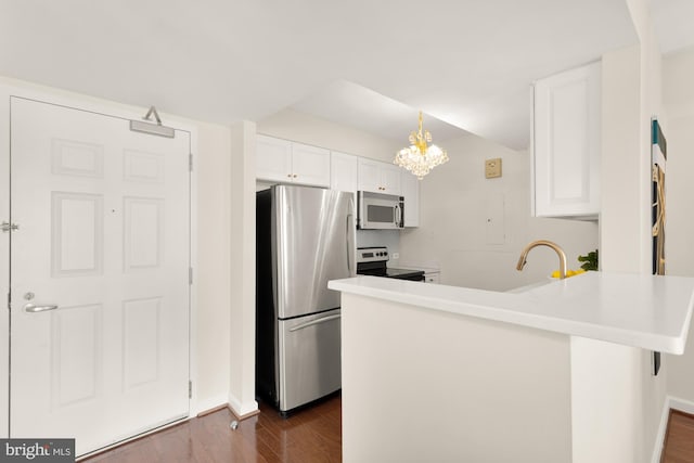 kitchen with appliances with stainless steel finishes, white cabinetry, hanging light fixtures, dark hardwood / wood-style floors, and kitchen peninsula