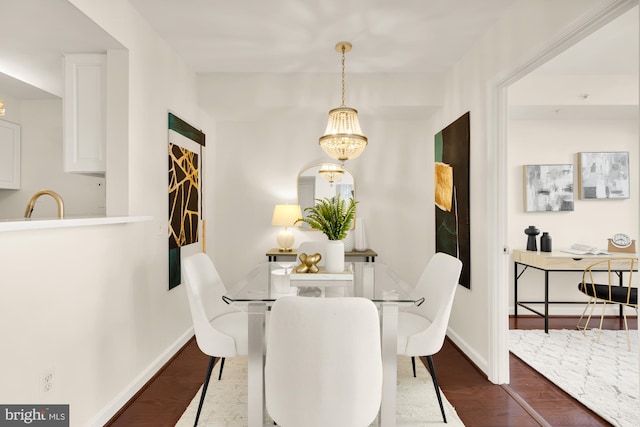 dining room with dark hardwood / wood-style floors, sink, and a notable chandelier