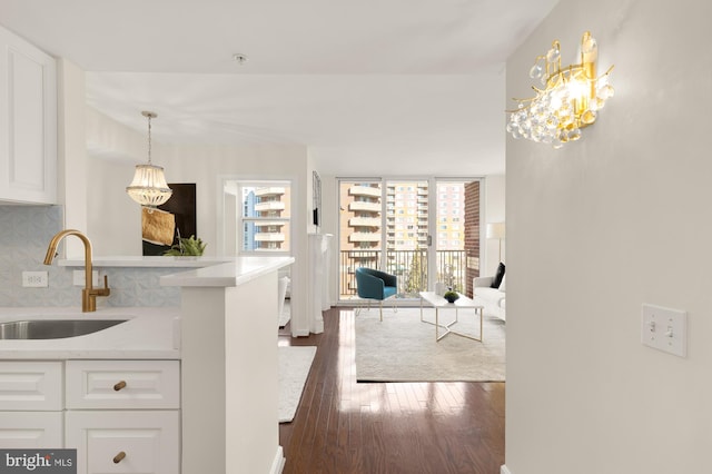 kitchen featuring dark wood-type flooring, sink, white cabinets, light stone countertops, and backsplash