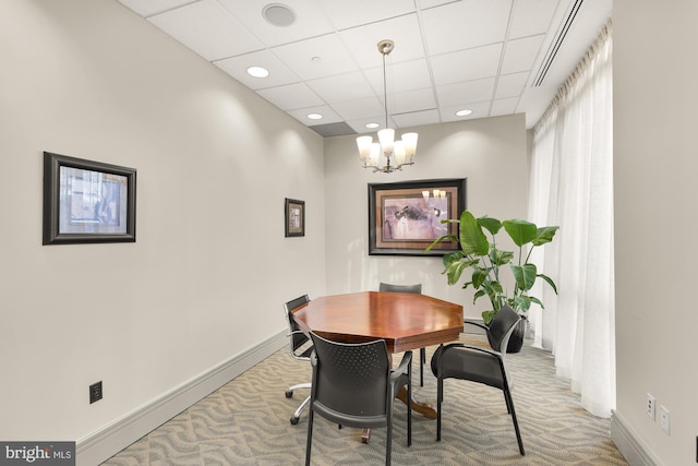 carpeted dining area featuring a paneled ceiling and an inviting chandelier