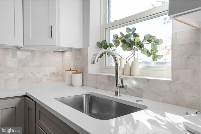 room details featuring backsplash, white cabinetry, and sink