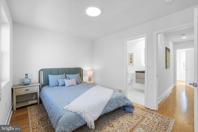 bedroom with hardwood / wood-style flooring and connected bathroom