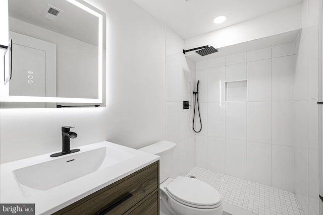 bathroom featuring vanity, toilet, and a tile shower