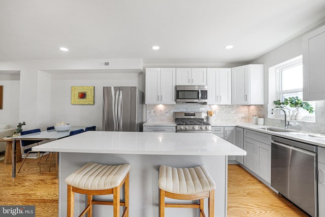 kitchen featuring a breakfast bar, sink, appliances with stainless steel finishes, and light hardwood / wood-style flooring