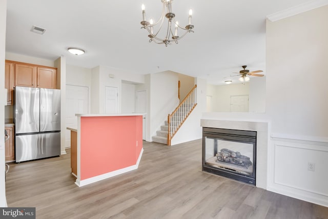 kitchen with a multi sided fireplace, stainless steel refrigerator, decorative light fixtures, a center island, and light hardwood / wood-style floors