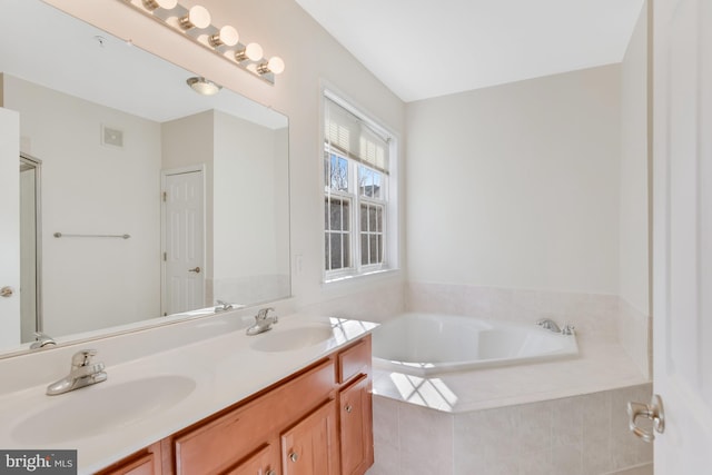 bathroom featuring tiled tub and vanity