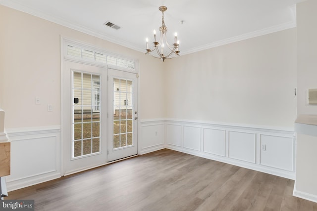 unfurnished dining area featuring ornamental molding, an inviting chandelier, and light hardwood / wood-style floors