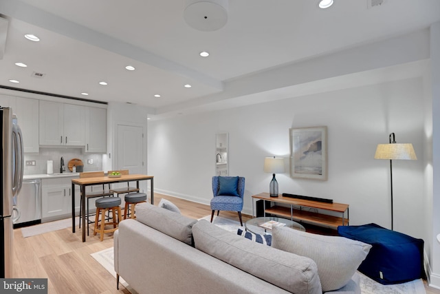 living room featuring sink and light hardwood / wood-style flooring