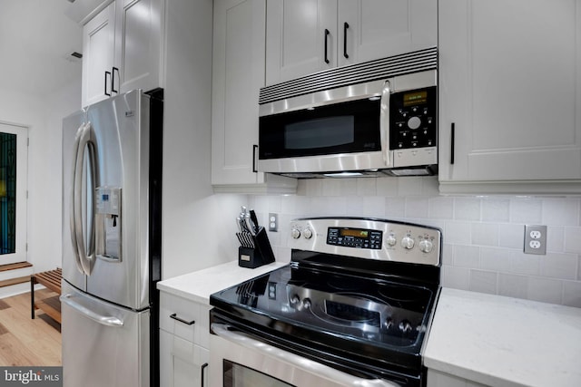 kitchen with decorative backsplash, stainless steel appliances, light hardwood / wood-style flooring, and light stone counters