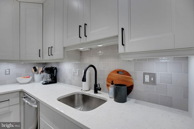 kitchen featuring light stone countertops, decorative backsplash, white cabinets, and sink