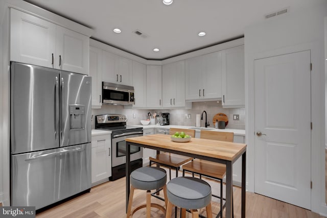 kitchen with white cabinets, appliances with stainless steel finishes, and light wood-type flooring