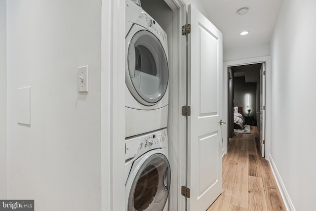 washroom featuring stacked washer and dryer and light wood-type flooring