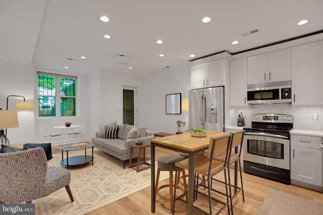 kitchen featuring white cabinets, appliances with stainless steel finishes, and light hardwood / wood-style flooring