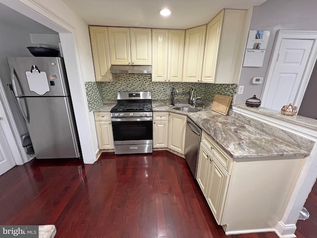 kitchen with light stone countertops, sink, tasteful backsplash, dark hardwood / wood-style floors, and appliances with stainless steel finishes