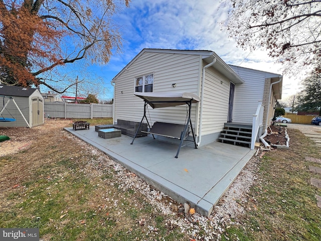 back of house featuring a patio, a fire pit, and a shed