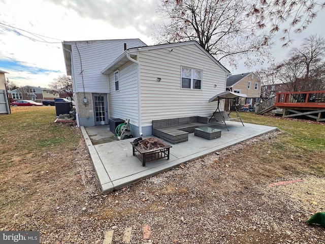 back of property with a patio area, a deck, and an outdoor living space with a fire pit