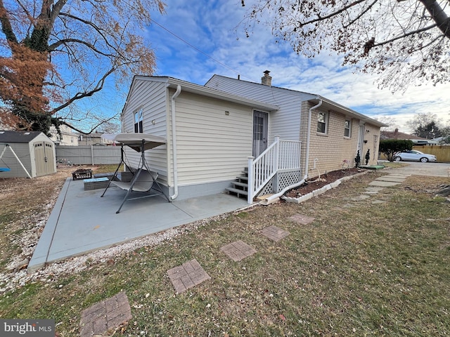 rear view of house featuring a lawn, a storage shed, and a patio