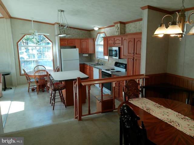 kitchen with white appliances, ceiling fan, sink, decorative light fixtures, and a center island