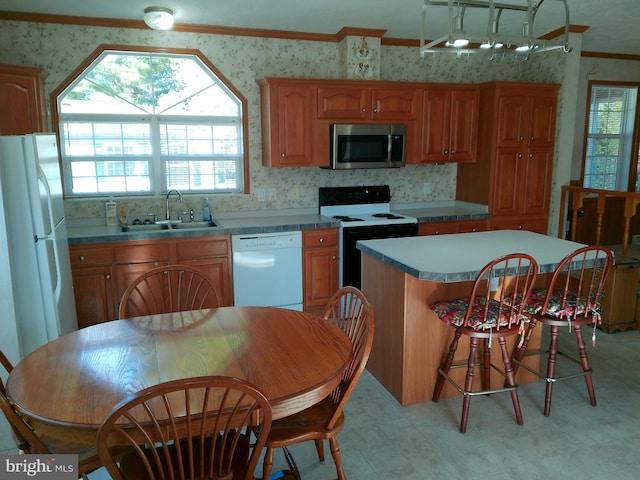 kitchen featuring a center island, white appliances, crown molding, sink, and a skylight