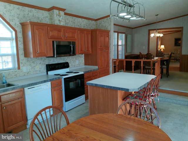 kitchen featuring hanging light fixtures, crown molding, a chandelier, white appliances, and a kitchen island