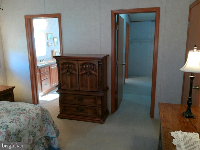 bedroom with a spacious closet, sink, and light carpet