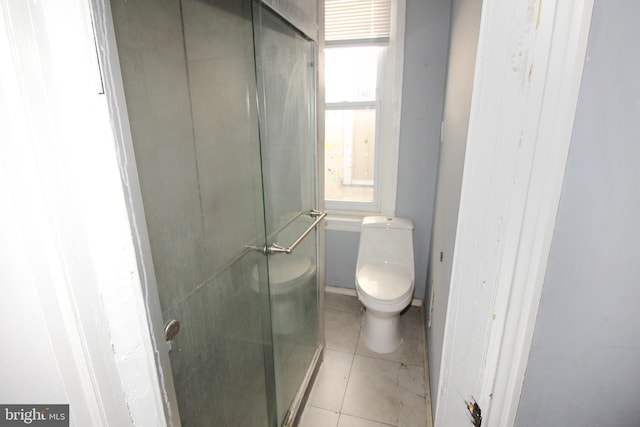 bathroom with tile patterned floors, a shower with door, and toilet