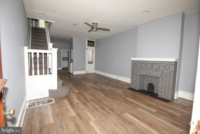 unfurnished living room with a fireplace, wood-type flooring, and ceiling fan