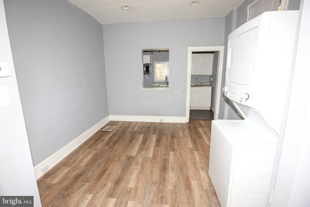 laundry room with light wood-type flooring and stacked washing maching and dryer