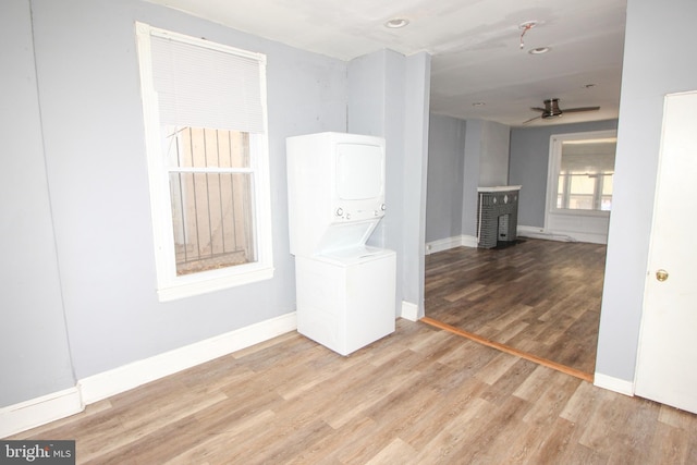 spare room featuring light hardwood / wood-style flooring, stacked washer / dryer, and ceiling fan