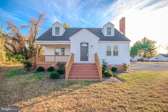 new england style home featuring covered porch and a front lawn