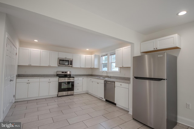 kitchen with appliances with stainless steel finishes, white cabinetry, and sink