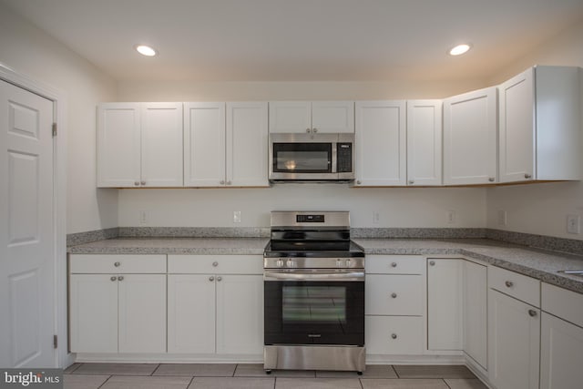 kitchen featuring stainless steel appliances, white cabinetry, and light tile patterned flooring