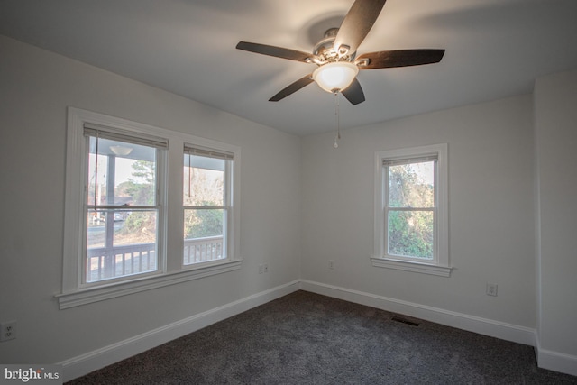 spare room featuring dark carpet and ceiling fan