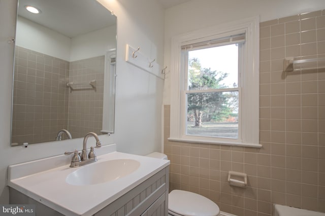 bathroom with plenty of natural light, vanity, tile walls, and toilet