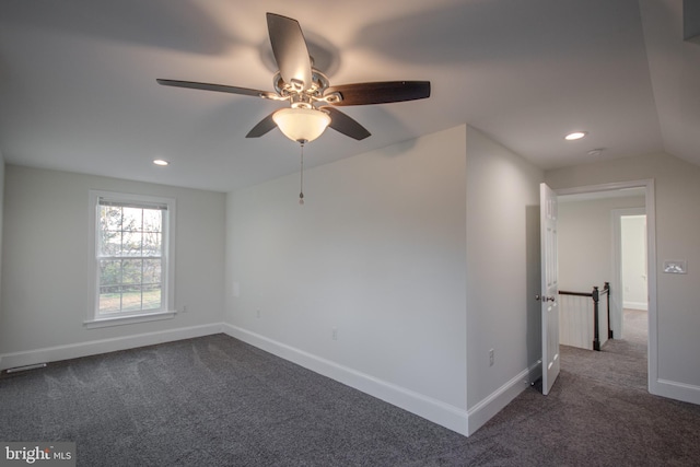 empty room featuring ceiling fan, dark carpet, and vaulted ceiling