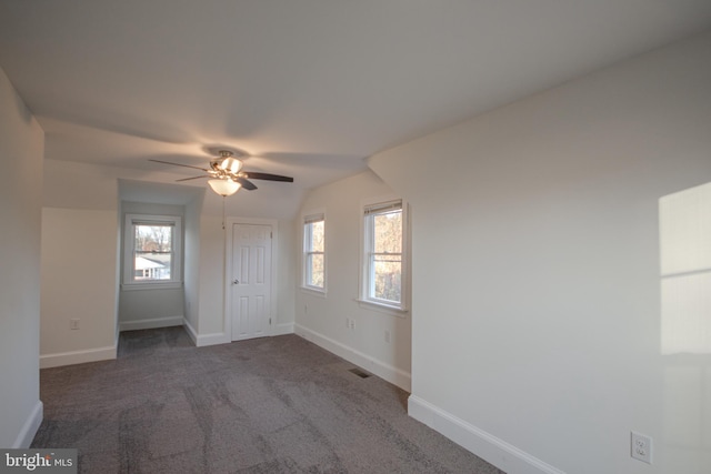 unfurnished room with dark colored carpet, plenty of natural light, ceiling fan, and vaulted ceiling