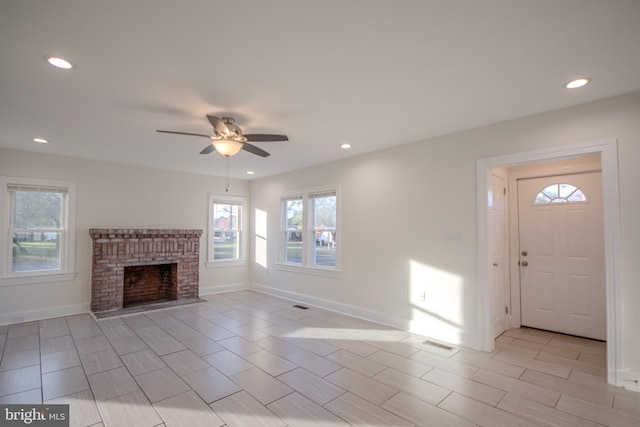 unfurnished living room featuring a brick fireplace and ceiling fan