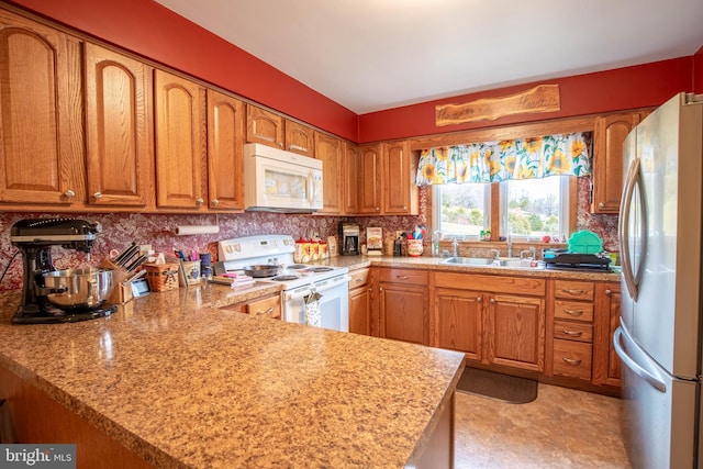 kitchen featuring kitchen peninsula, white appliances, light stone countertops, and sink