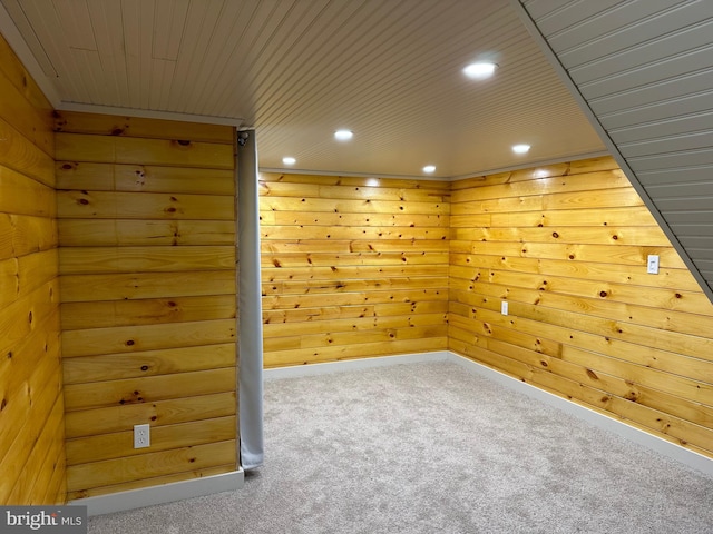 spare room featuring wood walls, carpet, and wooden ceiling