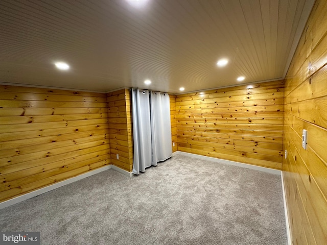 interior space featuring carpet, wooden walls, and wood ceiling