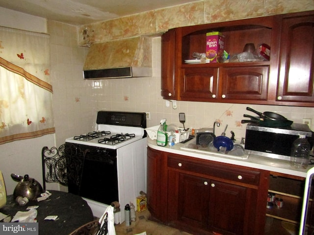 kitchen with white gas range, decorative backsplash, sink, and extractor fan