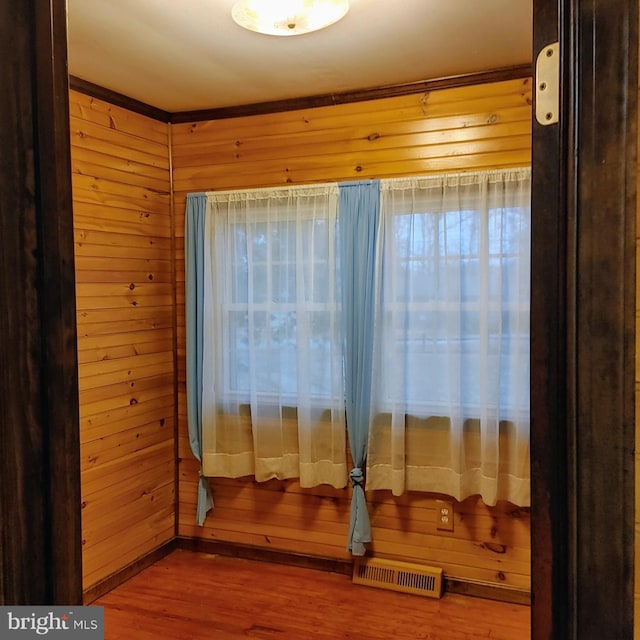 interior space with hardwood / wood-style flooring and wooden walls